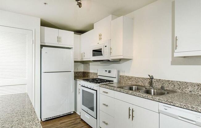 White cabinets with attached microwave on top of gas stove