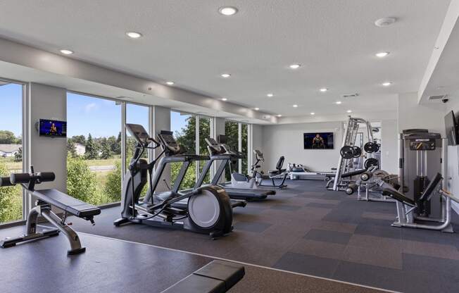 a gym with treadmills and other exercise equipment and windows