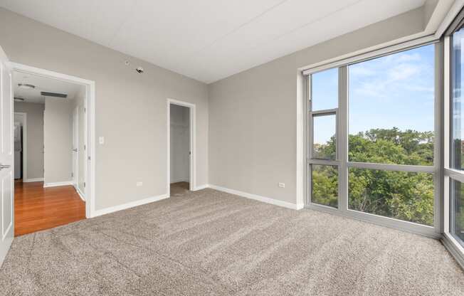 an empty living room with large windows and a rug