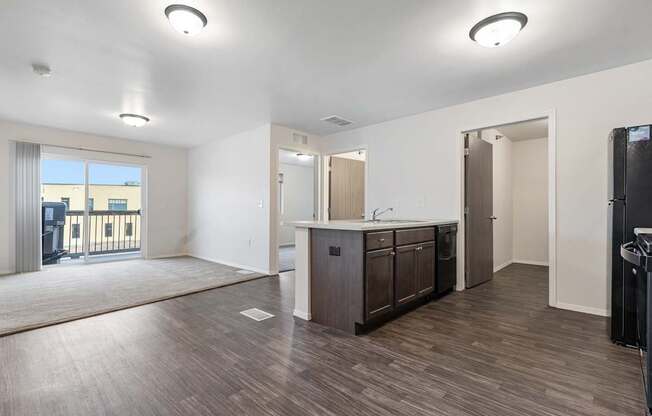 A spacious kitchen with dark wood floors and white walls.