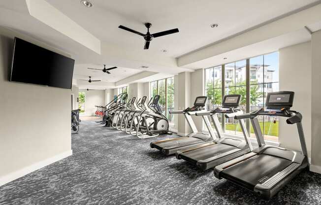 a gym with cardio machines and a tv