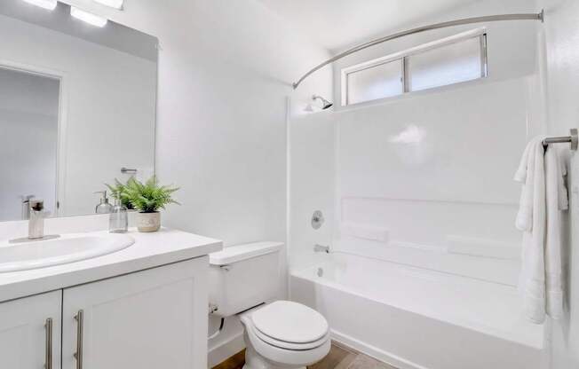 A white bathroom with a toilet, sink, and bathtub.