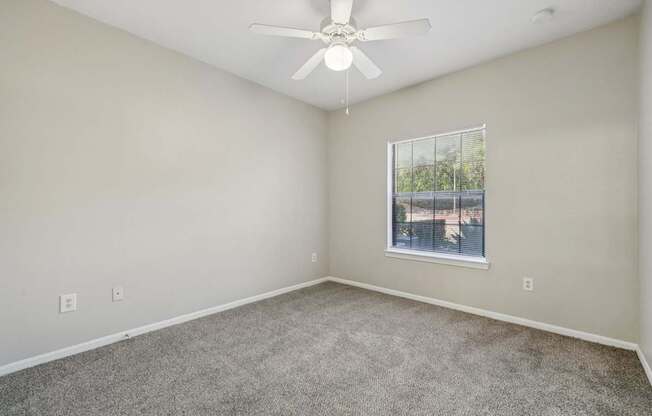 A room with a ceiling fan and a window.