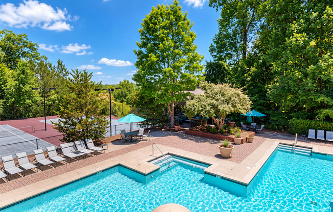 Swimming pool with lounge chairs, umbrella tables, and adjacent tennis courts at Elevation 3505 in Atlanta, GA.