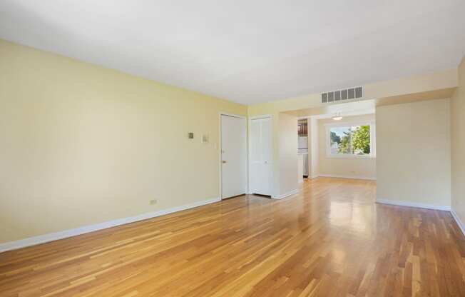 an empty living room with wood floors and white walls