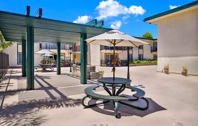 a patio with tables and umbrellas outside of a building at Camino de Oro Apartments, California, 90505