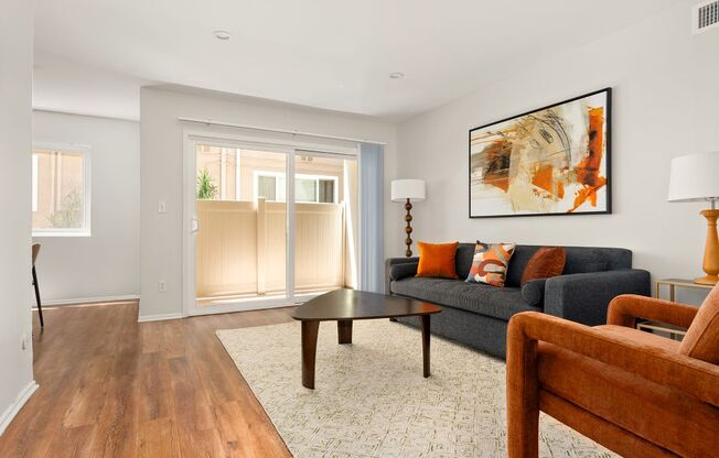 A living room with a couch, a chair, and a painting on the wall.