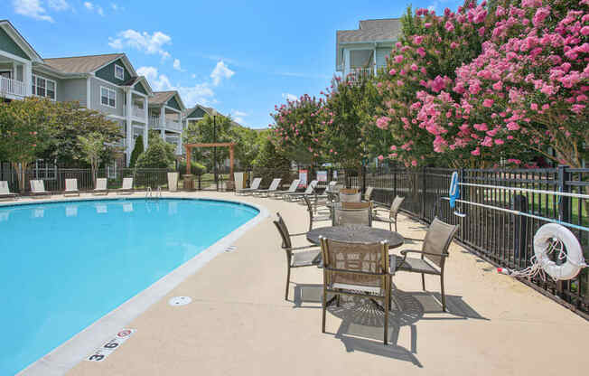 a swimming pool with a table and chairs next to a building