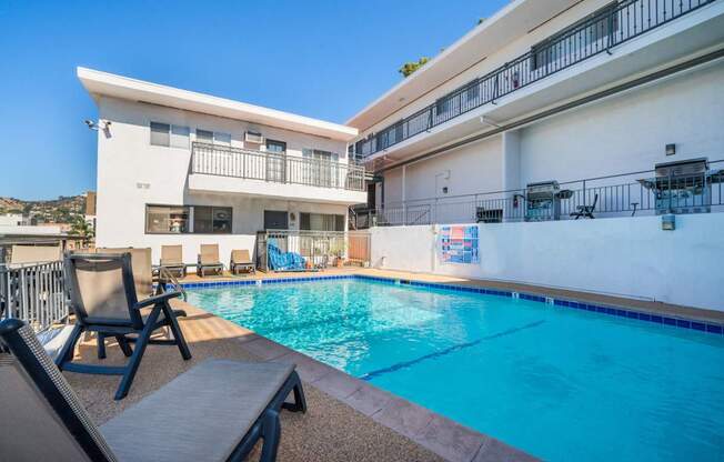 A swimming pool in front of a white building with a blue sky in the background.