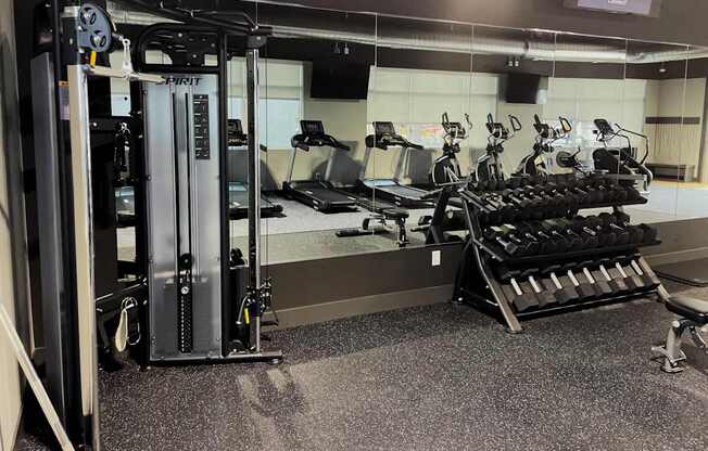 A gym with a variety of equipment including a squat rack, leg press, and a bench press.