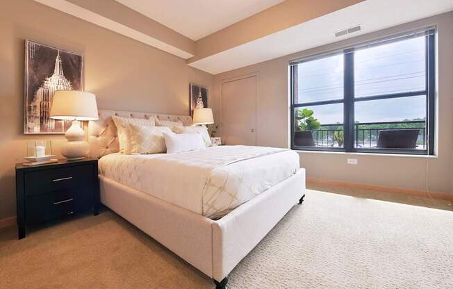 A bedroom with a large bed and a window overlooking a balcony.