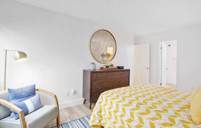 A bedroom with a bed, chair, and dresser at Verandas Apartments, West Covina, California