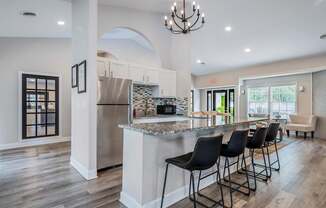 A kitchen with a bar and chairs.