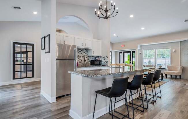 A kitchen with a bar and chairs.