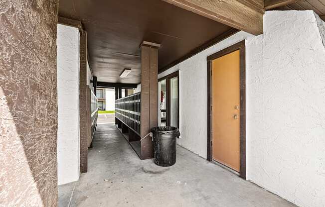 A hallway with a brown door and a black trash can.