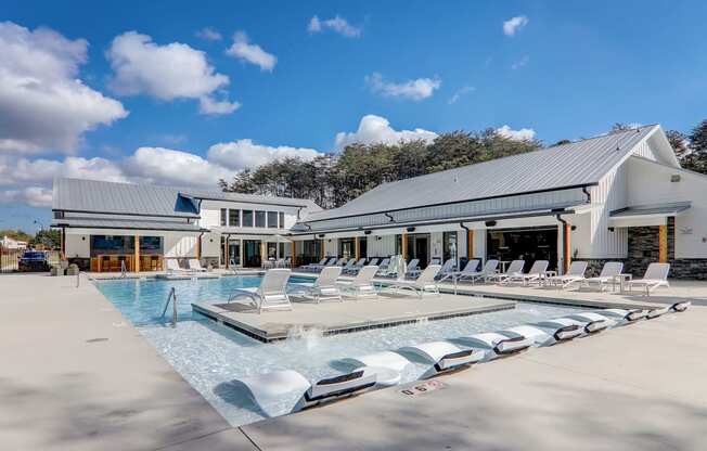 the resort style pool is outside of a white building with white lounge chairs