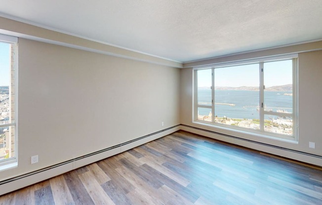 an empty living room with a large window and a view of the water