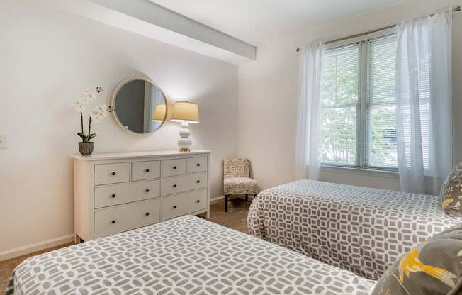 a bedroom with two beds and a dresser with a mirror at Pier Village Apartments, Long Branch, 07740