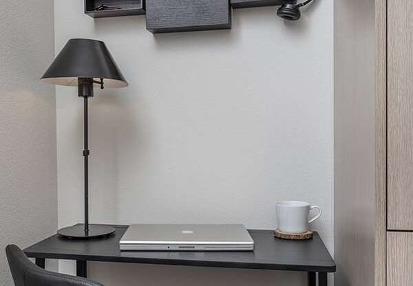 a desk with a laptop and a lamp on top of it