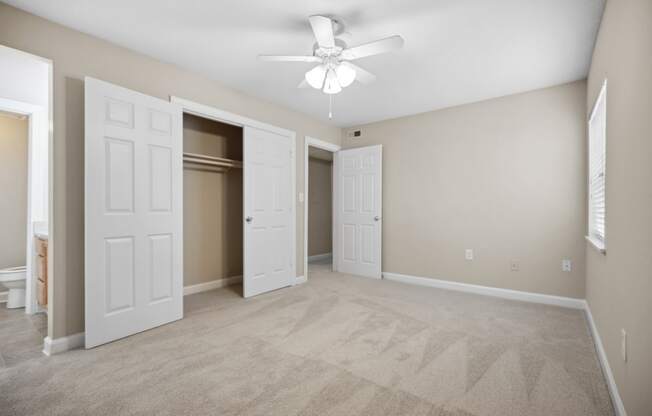 an empty living room with white doors and a ceiling fan