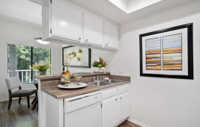 a kitchen with white cabinetry and a white dishwasher