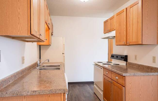 A kitchen with wooden cabinets and a granite countertop. West Fargo, ND Saddlebrook Apartments