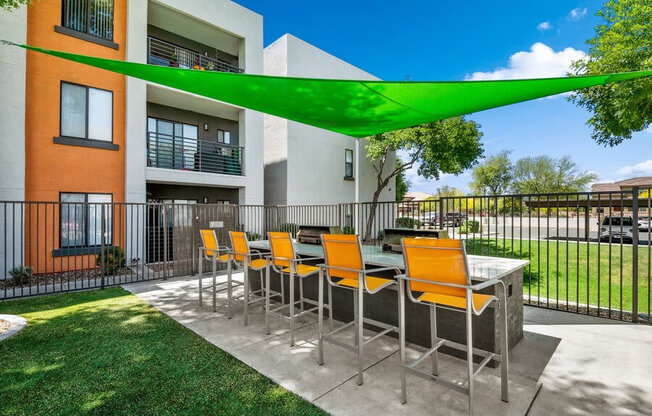 Outdoor BBQ Area with Furniture and Green Canopy at Harmony at Surprise Apartments in Surprise, AZ.