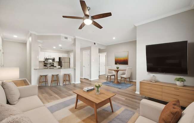 A living room with a ceiling fan and a flat screen TV.