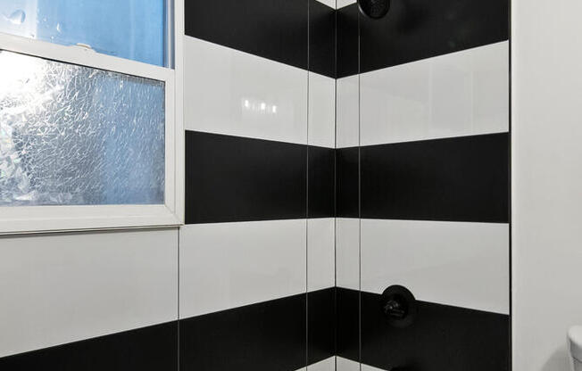 A black and white striped bathroom with a tub and toilet at Brookmore.