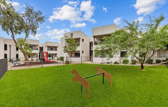 a yard with a seesaw and a dog statue in front of a building