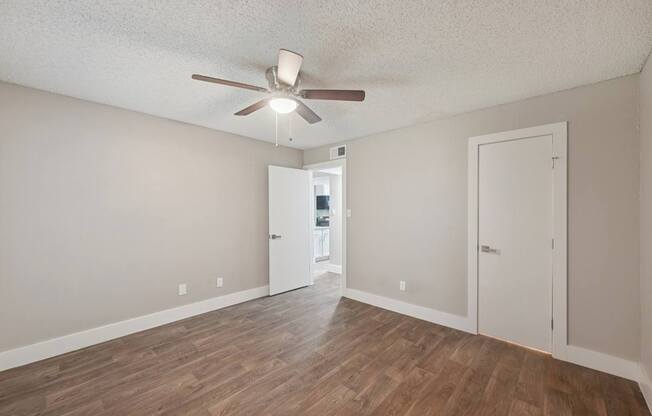A room with a ceiling fan and wooden flooring.