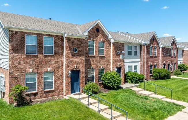 A row of red brick houses with green lawns in front.