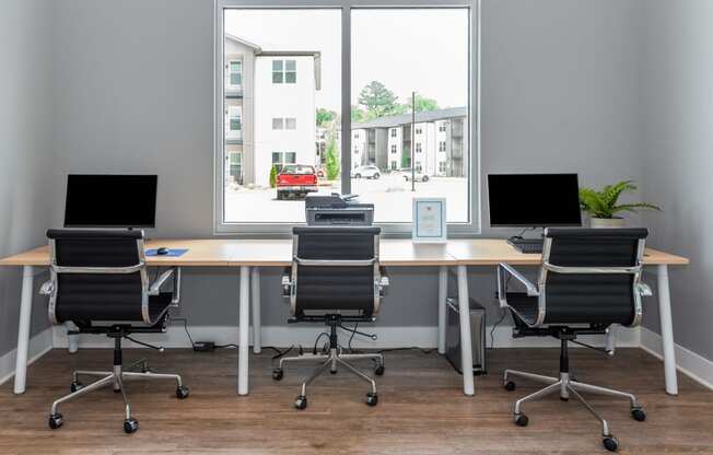 an empty office with three desks and chairs and a window