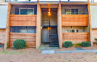A two-story wooden house with a black staircase leading to the entrance.