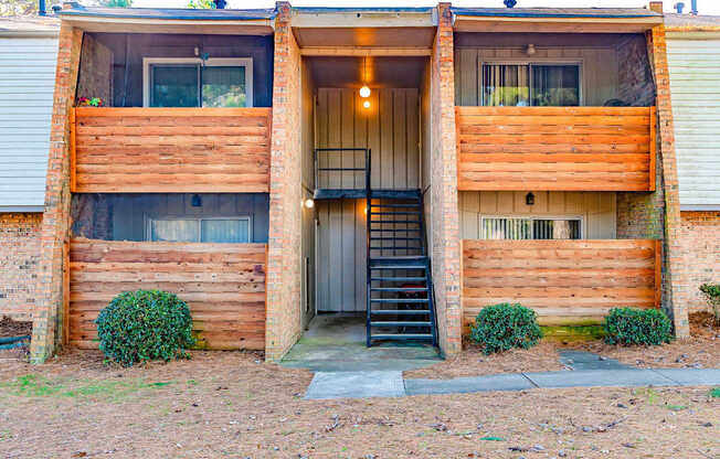 A two-story wooden house with a black staircase leading to the entrance.