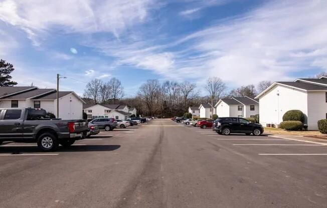 a city street with cars parked in a parking lot at Cleo Apartments, Alabama, 35611