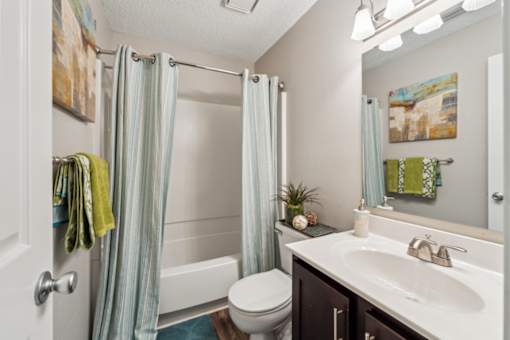 A bathroom with a white toilet, a sink, and a shower with a blue shower curtain.