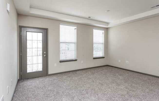 an empty living room with three windows and a door