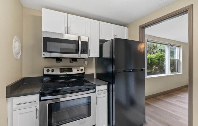 A black refrigerator stands next to a stove in a kitchen.
