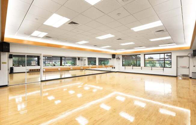 A spacious dance studio with wooden floors and mirrors on the walls.