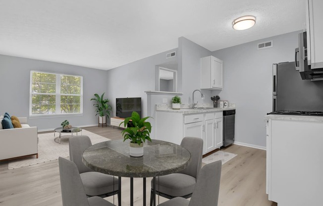 a dining area with a table and chairs and a kitchen in the background