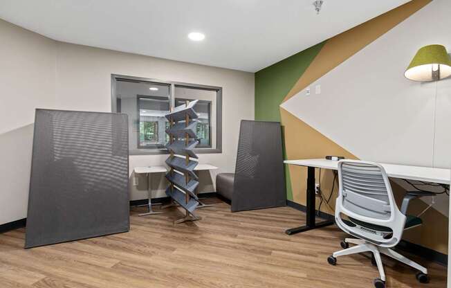 A room with a desk, chairs, and a window.