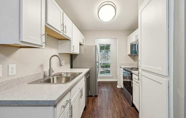 A kitchen with white cabinets and a wooden floor.