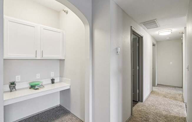 A hallway with a white cabinet and a grey carpet.