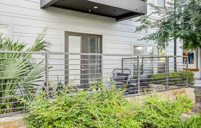 a patio with chairs and a fence in front of a house