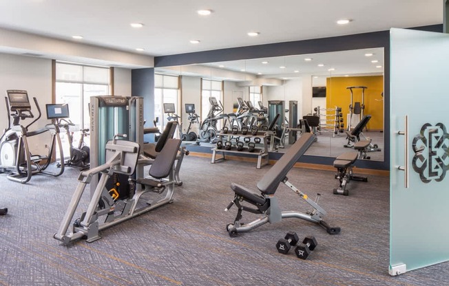 A gym with a variety of equipment including treadmills, weights, and exercise machines.