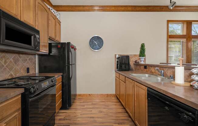 A kitchen with black appliances and wooden cabinets.