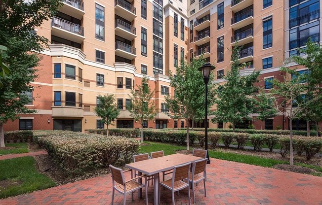 a patio with a table and chairs in front of an apartment building