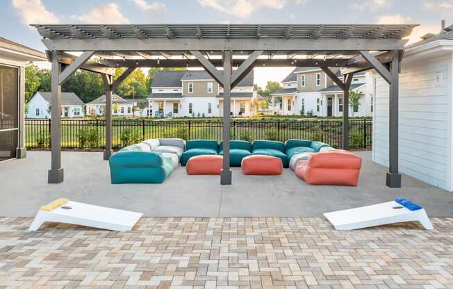 a patio with couches and a pergola with houses in the background