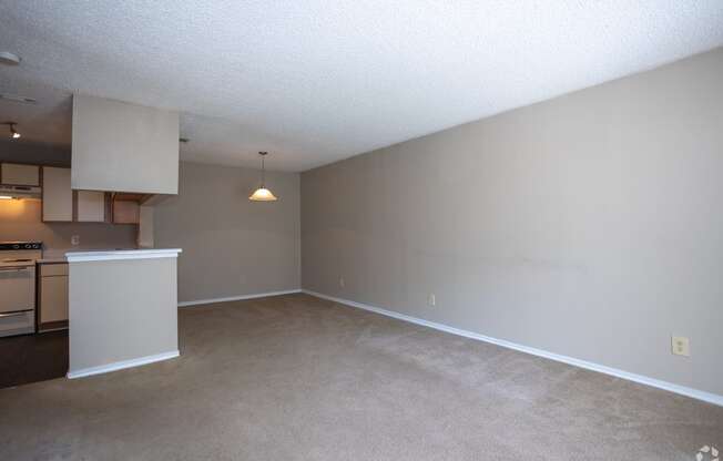 an empty living room and kitchen with a white counter top